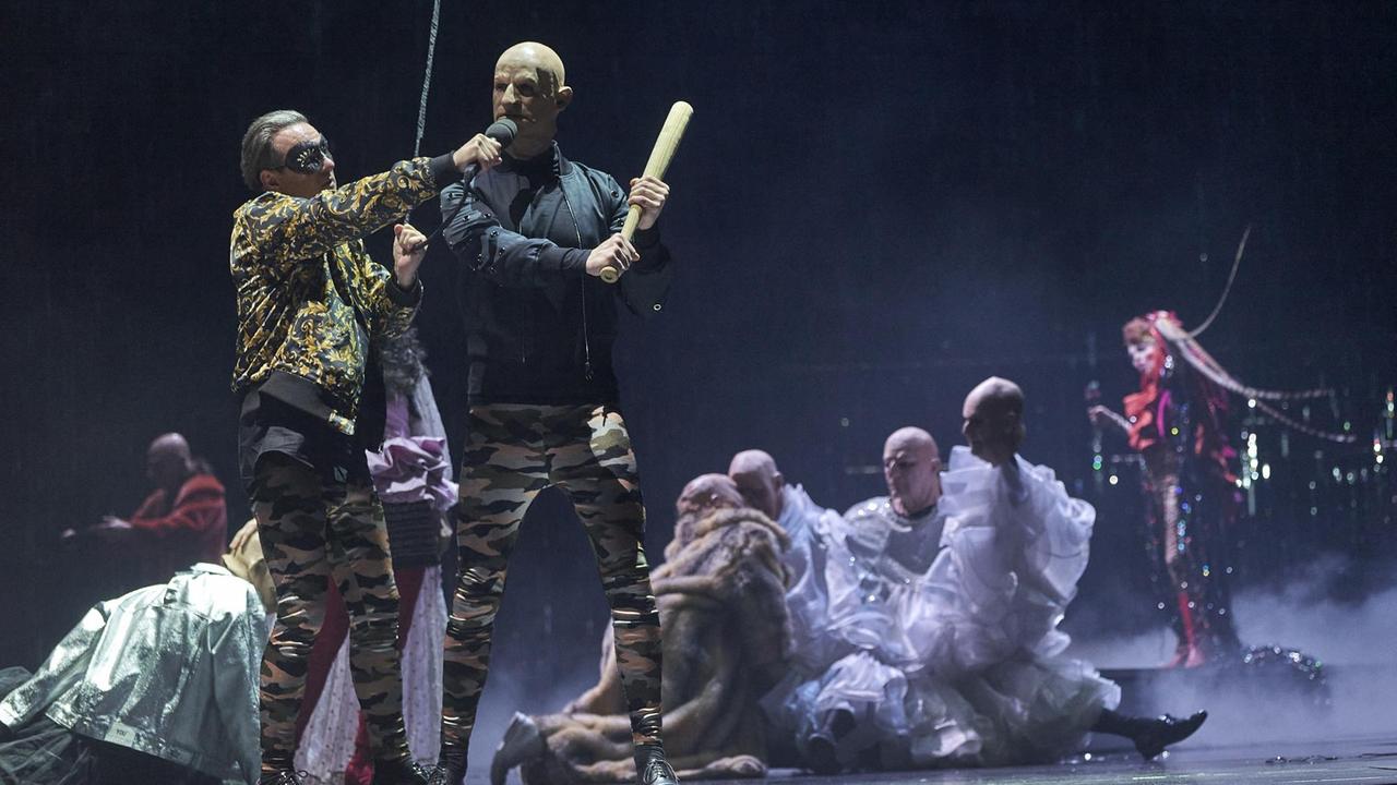 Szenenbild der Inszenierung "THIS IS VENICE" in der Regie von Sebastian Nübling am Wiener Burgtheater mit den Schauspielern Norman Hacker und Dietmar König im Vordergrund und dem Ensemble dahinter. Szenenbild der Inszenierung "THIS IS VENICE" in der Regie von Sebastian Nübling am Wiener Burgtheater mit den Schauspielern Norman Hacker und Dietmar König im Vordergrund und dem Ensemble dahinter.