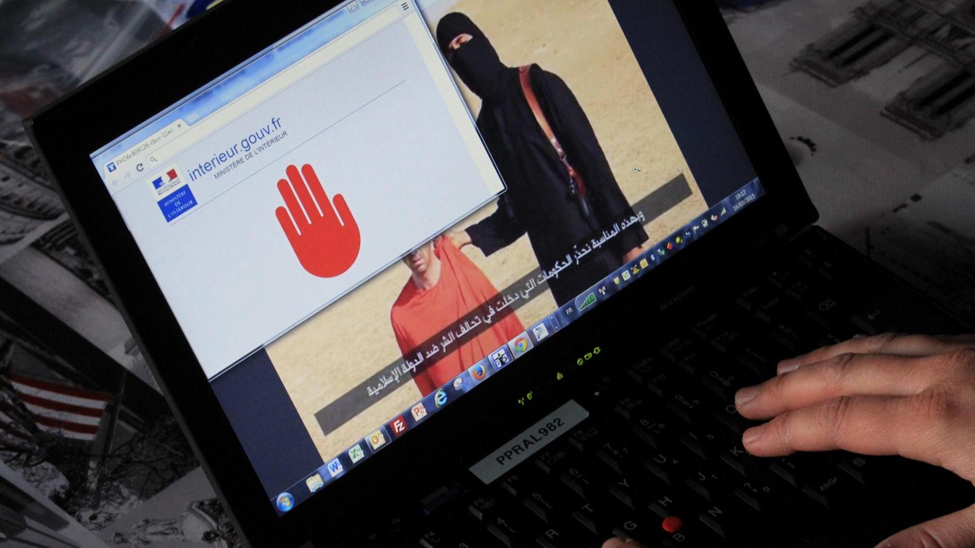 Auf einem Laptopbildschirm sieht man im Hintergrund einen komplett schwarz verhüllten Mann, der eine Waffe umgehängt hat. Er hält einen Mann in orangener Gefangenenkleidung fest, der vor ihm kniet. Im Vordergrund öffnet sich eine Seite der französischen Regierung, auf der eine rote Hand eine Sperre signalisiert. Auf einem Laptopbildschirm sieht man im Hintergrund einen komplett schwarz verhüllten Mann, der eine Waffe umgehängt hat. Er hält einen Mann in orangener Gefangenenkleidung fest, der vor ihm kniet. Im Vordergrund öffnet sich eine Seite der französischen Regierung, auf der eine rote Hand eine Sperre signalisiert.