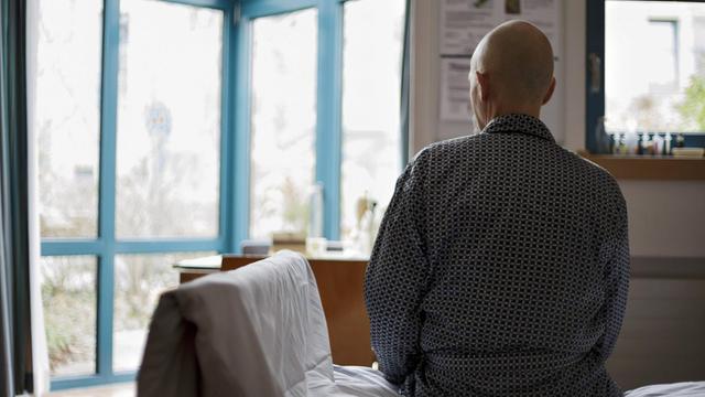 Ein Krebspatient sitzt im Palliativzentrum der Uniklinik Köln, einer Einrichtung, die todkranke Menschen beim Sterben begleitet, auf einem Bett