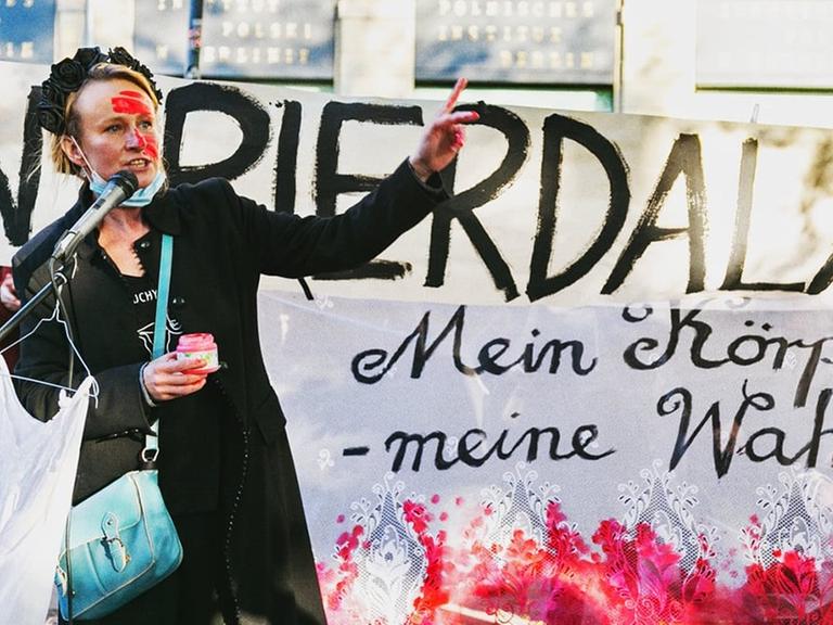 Die Aktionskünstlerin Anna Krenz in Berlin vor einem Transparent mit der Aufschrift "Mein Körper - meine Wahl".
