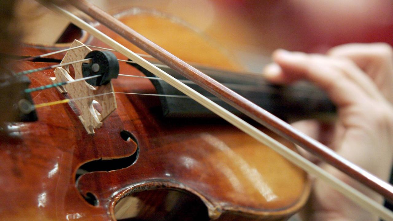 Eine Hand hält eine Geige beim Geigenspiel.
