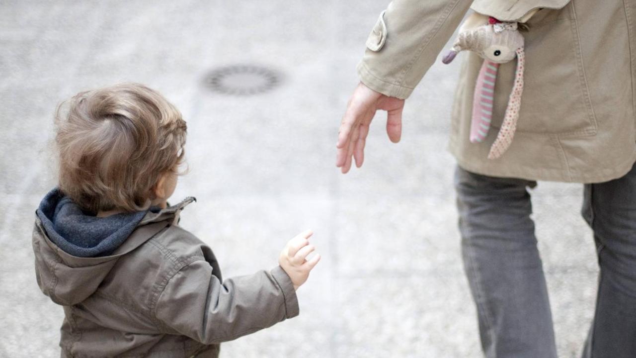 Ein Vater streckt die Hand nach seinem Kind aus.