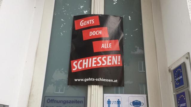 Ein Plakat klebt an der Tür mit der Aufschrift: "Geht doch alle Schiessen!"