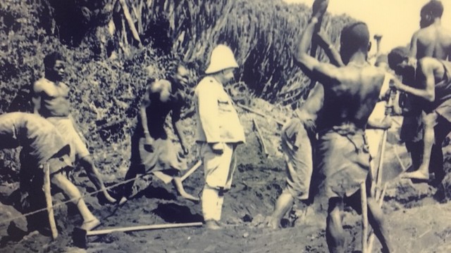 Europäer in Uniform beaufsichtigt afrikanische Landarbeiter Europäer in Uniform beaufsichtigt afrikanische Landarbeiter