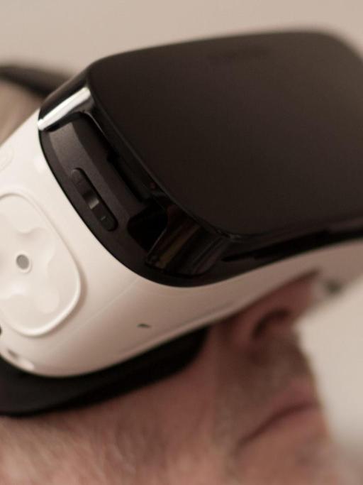 Ein Mann trägt eine VR-Brille und ist in eine räumliche, virtuelle Welt eingetaucht.