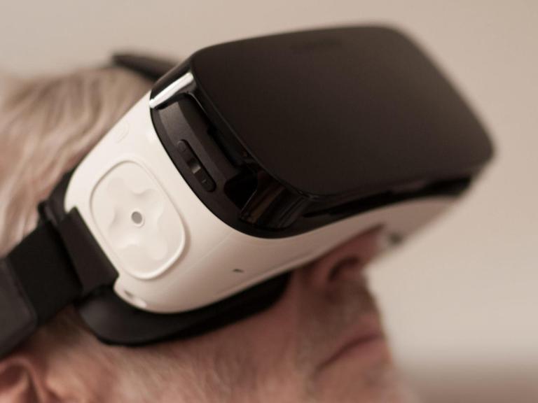 Ein Mann trägt eine VR-Brille und ist in eine räumliche, virtuelle Welt eingetaucht.