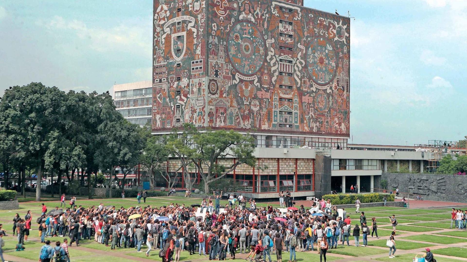Die Zentralbibliothek der Nationalen Autonomen Universität von Mexiko, davor Studenten auf dem Campus.