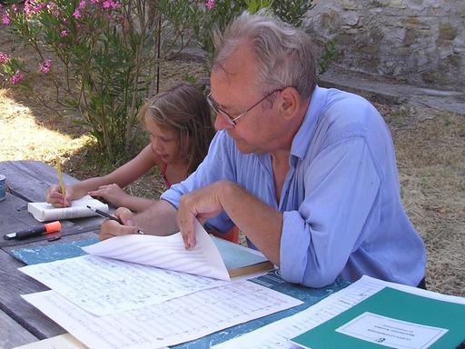 Das Bild zeigt den Komponisten bei der Arbeit; neben ihm sitzt seine kleine Tochter.