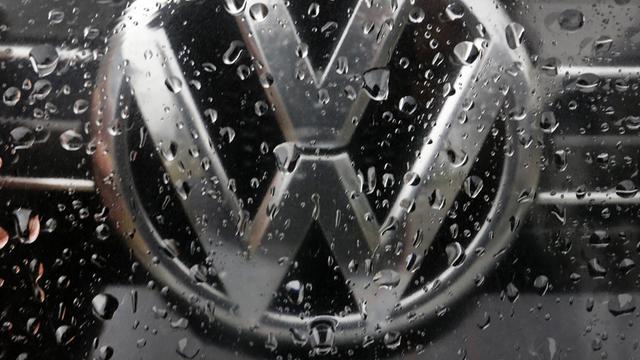 Das Bild zeigt ein VW-Logo auf einem Auto. Es ist voller Regentropfen.