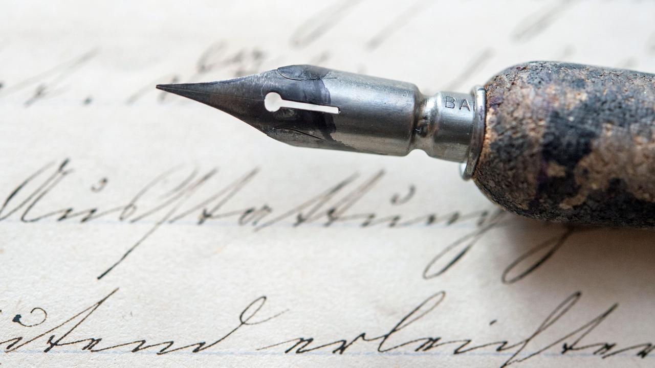 Im Büro des Schriftexperten Klaus-Dieter Stellmacher aus Cottbus (Brandenburg) ist eine alte Spitzfeder auf einem Schreibheft von 1880 zu sehen. Im Büro des Schriftexperten Klaus-Dieter Stellmacher aus Cottbus (Brandenburg) ist eine alte Spitzfeder auf einem Schreibheft von 1880 zu sehen.