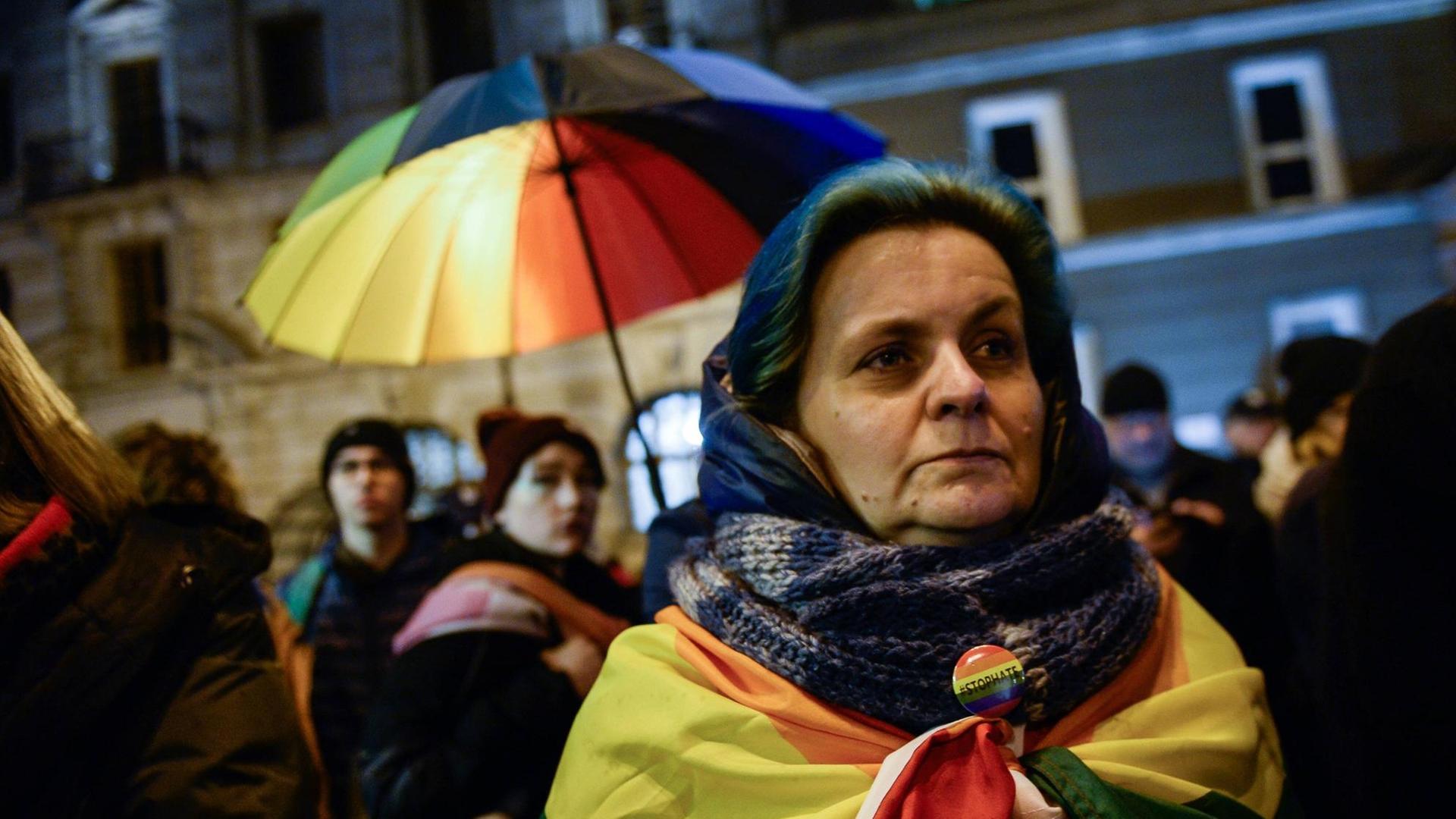 Ein Frau in Warschau hat eine Regenbogenflagge um sich gewickelt. Im Hintergrund weitere Demonstranten. Sie demonstrieren gegen LGBT-freie Zonen in Polen. Ein Frau in Warschau hat eine Regenbogenflagge um sich gewickelt. Im Hintergrund weitere Demonstranten. Sie demonstrieren gegen LGBT-freie Zonen in Polen.