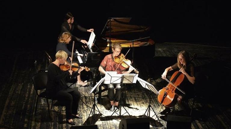 Die Interpretinnen sitzen spielend im Scheinwerferlicht auf der Bühne Die Interpretinnen sitzen spielend im Scheinwerferlicht auf der Bühne