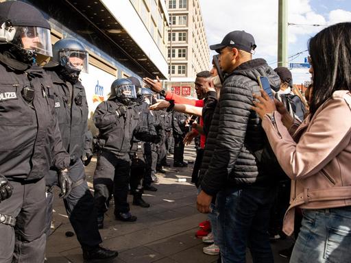 Polizisten und schwarze Demonstranten stehen sich in Berlin gegenüber.