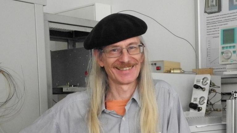 Mann mit Hut neben technischen Gerät Mann mit Hut neben technischen Gerät