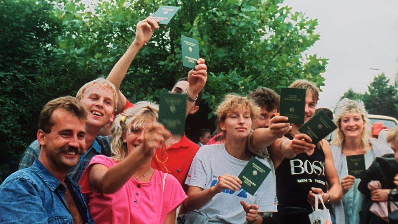 Jubelnde DDR-Flüchtlinge mit ihren Reisepässen in Österreich. Etwa 600 DDR-Bürger nutzten ein paneuropäisches Picknick an der ungarisch-österreichischen Grenze, bei dem ein Grenztor symbolisch geöffnet wurde, zur Flucht in den Westen. Jubelnde DDR-Flüchtlinge mit ihren Reisepässen in Österreich. Etwa 600 DDR-Bürger nutzten ein paneuropäisches Picknick an der ungarisch-österreichischen Grenze, bei dem ein Grenztor symbolisch geöffnet wurde, zur Flucht in den Westen.