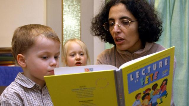 Eine Erzieherin liest Kindern aus einem französischem Märchenbuch vor