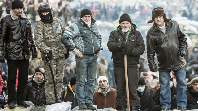Fünf Männer stehen auf Sandsäcken in der Gruschewsky-Straße in Kiew, es sind Anhänger der Opposition.