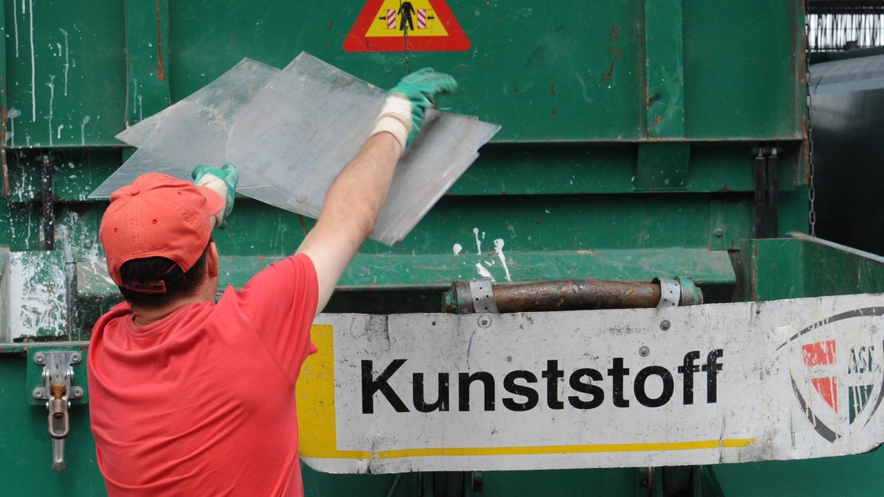 Ein Mann wirft auf dem Recyclinghof Kunststoff in einen Sammelbehälter.