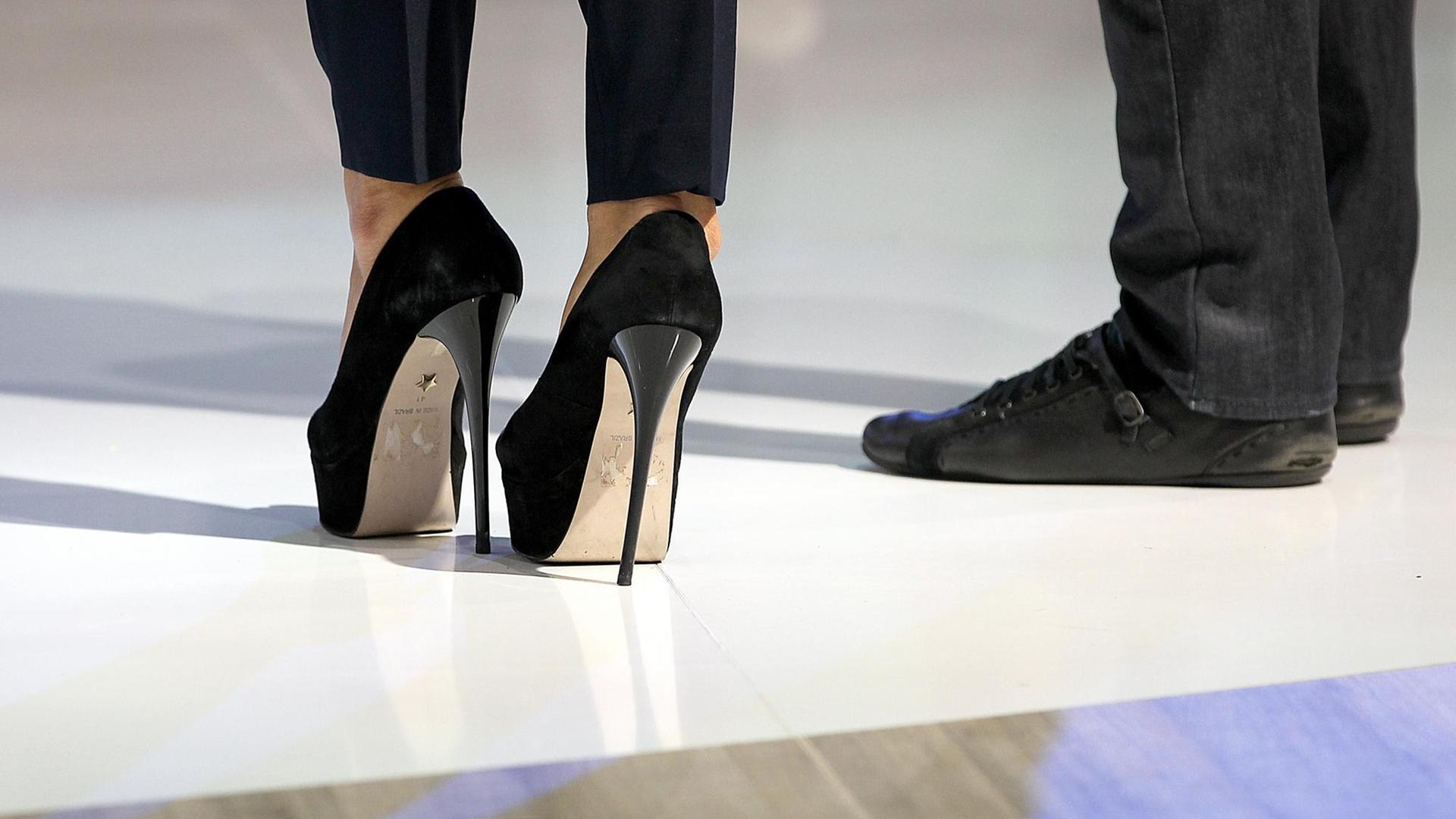 Frau in High Heels, Mann in bequemen Schuhen. Frau in High Heels, Mann in bequemen Schuhen.