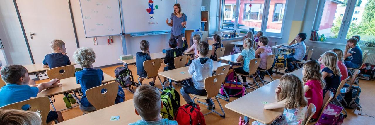 Kinder schauen zu ihrer Lehrerin an der Tafel. Kinder schauen zu ihrer Lehrerin an der Tafel.