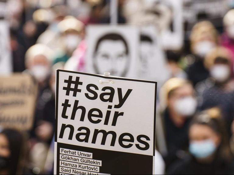 Ein Plakat „#say their names“ wird auf der Kundgebung zum Gedenken an den rassistischen Anschlag im Februar 2020 in Hanau hochgehalten.