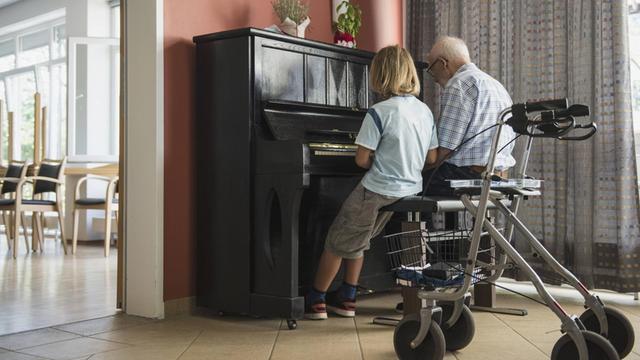 Ein Großvater gibt seinem Enkel eine Klavierstunde.