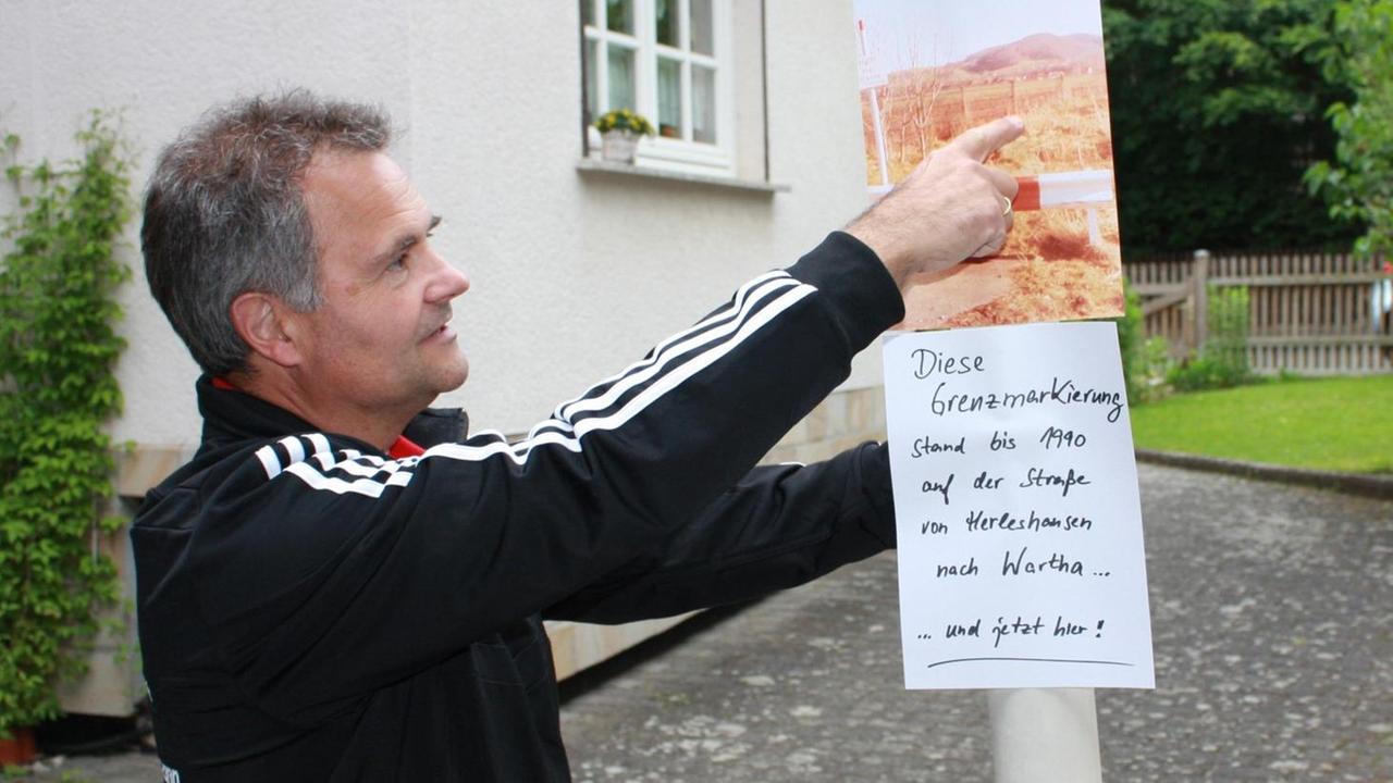 Ein Mann steht neben einem ehemaligen Mast der deutsch-deutschen Grenze, den er auf seinem Grundstück als Erinnerung an die deutsch-deutsche Teilung aufgestellt hat. Ein Mann steht neben einem ehemaligen Mast der deutsch-deutschen Grenze, den er auf seinem Grundstück als Erinnerung an die deutsch-deutsche Teilung aufgestellt hat.