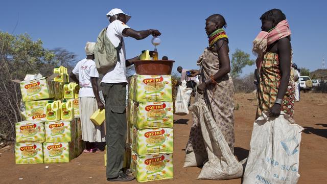Zwei Frauen aus Kenia stehen mit großen Säcken an einer Stelle für Nahrungsmittelverteilung
