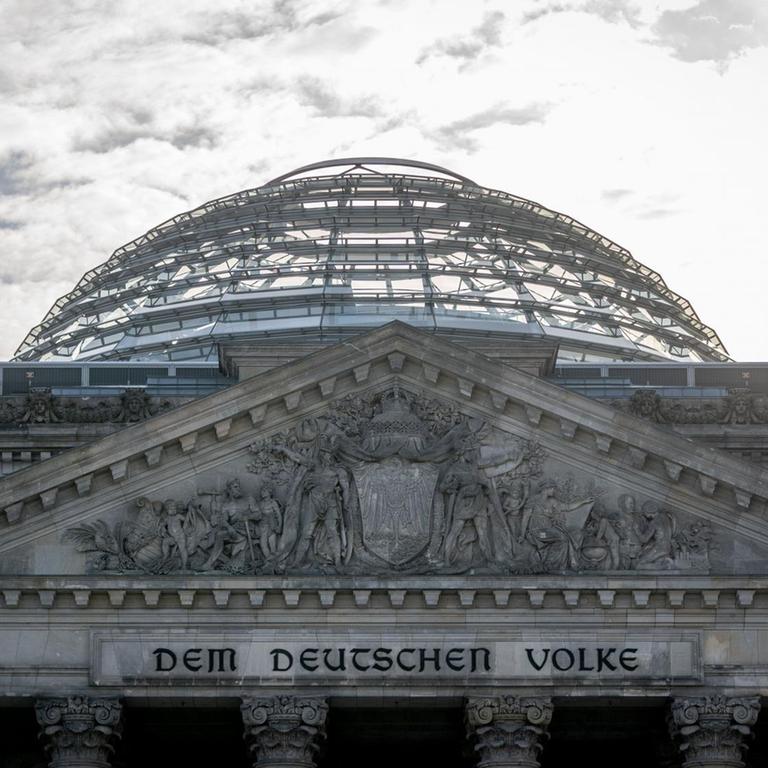 Die Sonne steht an einem Morgen hinter dem Reichstagsgebäude mit dem Bundestag in Berlin