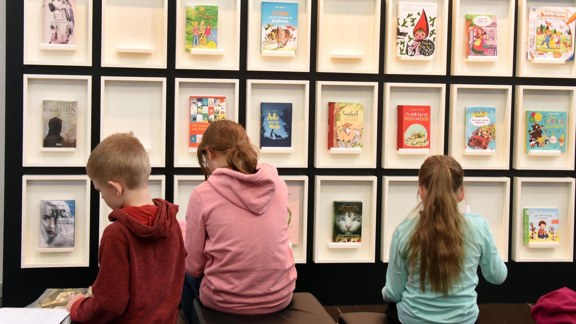 18.03.2018, Sachsen, Leipzig: Kinder lesen in Büchern an einem Stand auf der Leipziger Buchmesse. Foto: Waltraud Grubitzsch/dpa-Zentralbild/ZB