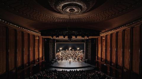 Das Orchester ist im imposanten Theaterraum der Volksbühne zu sehen.