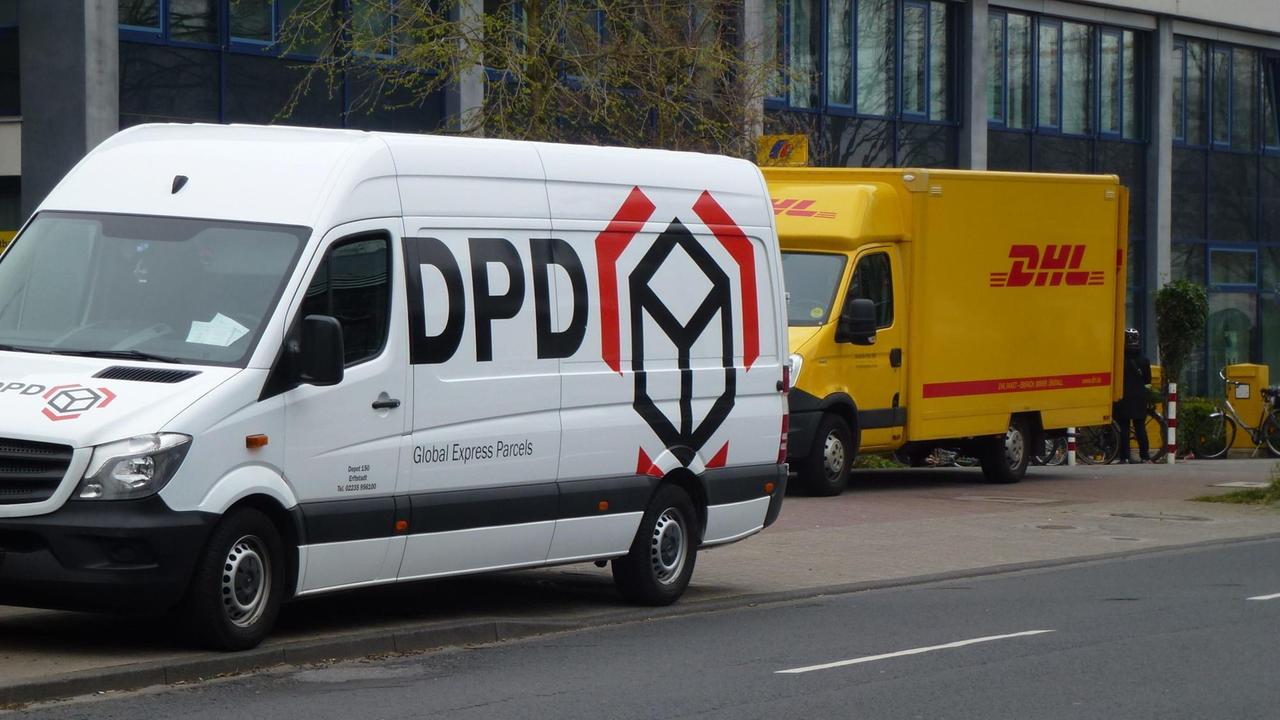 Fahrzeuge des Paketdienst DPD und DHL stehen nebeneinander am Strassenrand in Köln.