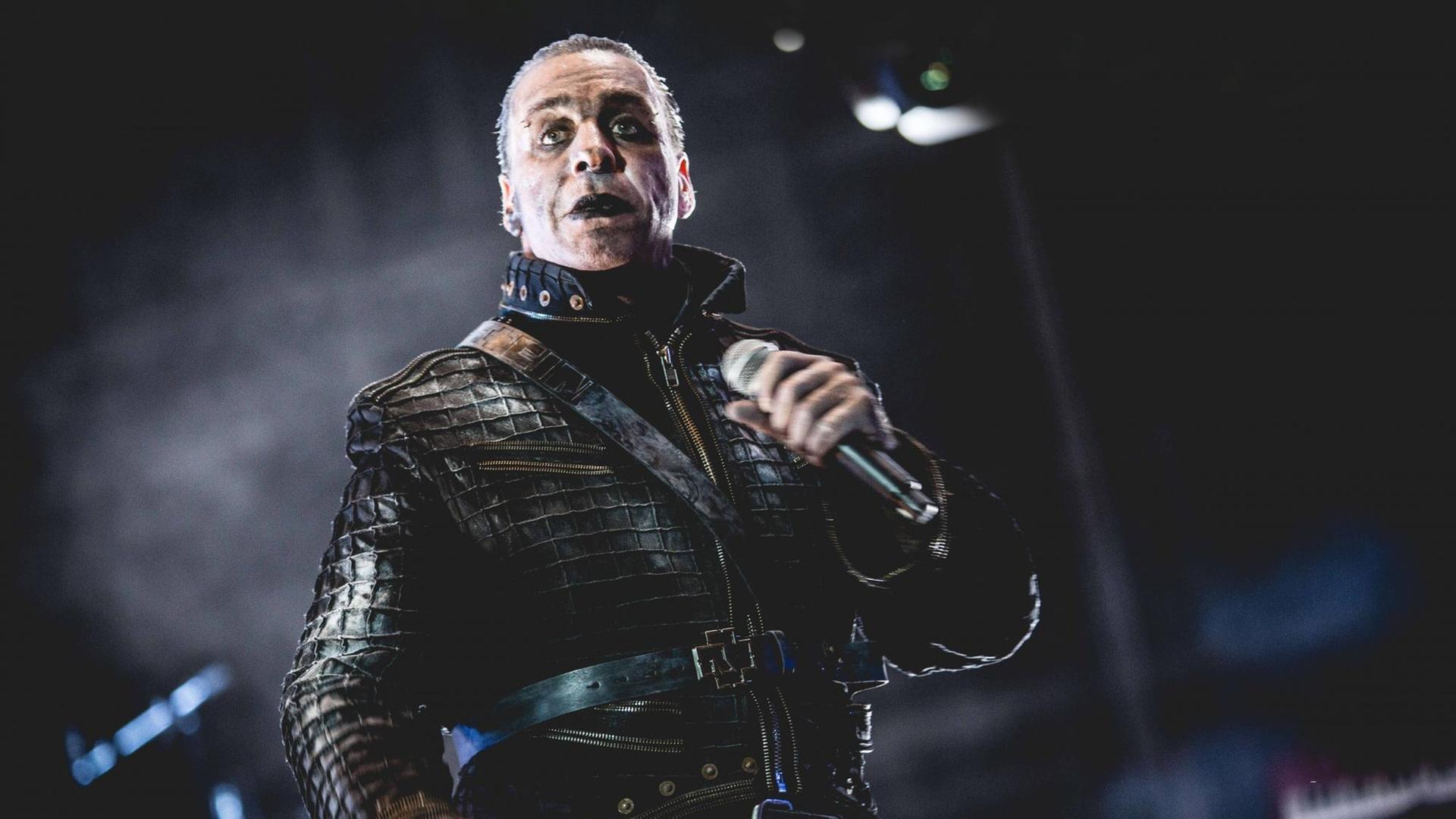 Der Sänger Till Lindemann düster geschminkt und mit Leder bekleidet steht auf der Bühne. Der Sänger Till Lindemann düster geschminkt und mit Leder bekleidet steht auf der Bühne.