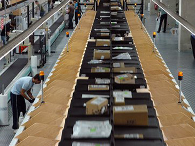 Arbeiter entleeren am Flughafen Köln/Bonn im Distributionszentrum eines Frachtdienstleisters die Faecher der automatischen Sortieranlage für Pakete und Briefe Arbeiter entleeren am Flughafen Köln/Bonn im Distributionszentrum eines Frachtdienstleisters die Faecher der automatischen Sortieranlage für Pakete und Briefe