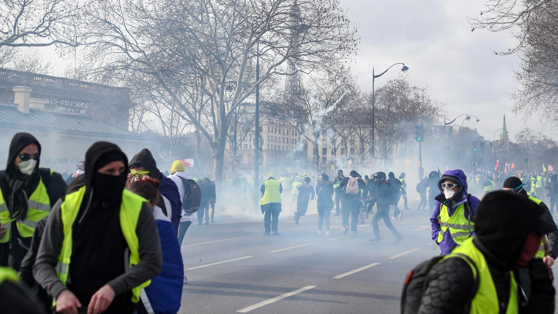 Anhänger der "Gelbwesten"-Bewegung protestieren im Tränengasnebel in der Nähe des Eifelturms in Paris. Anhänger der "Gelbwesten"-Bewegung protestieren im Tränengasnebel in der Nähe des Eifelturms in Paris.