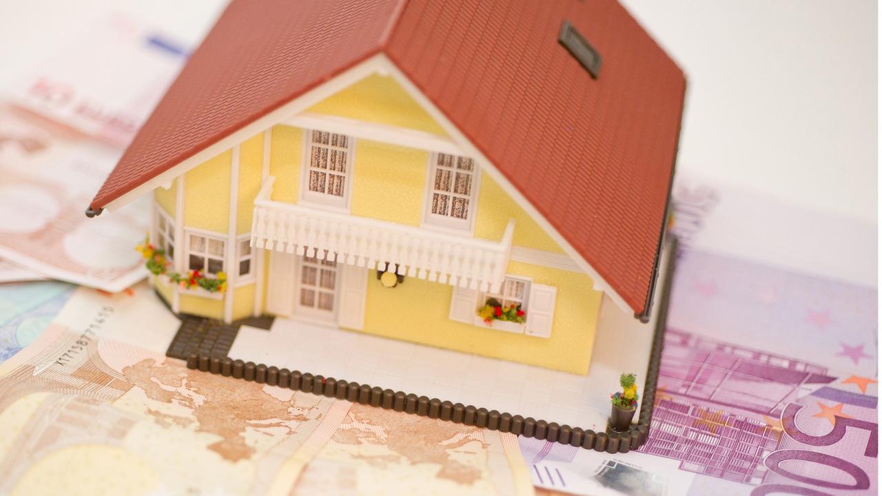Ein Haus steht auf Geldscheinen. Symbolbild für Haus und seine Kosten Ein Haus steht auf Geldscheinen. Symbolbild für Haus und seine Kosten