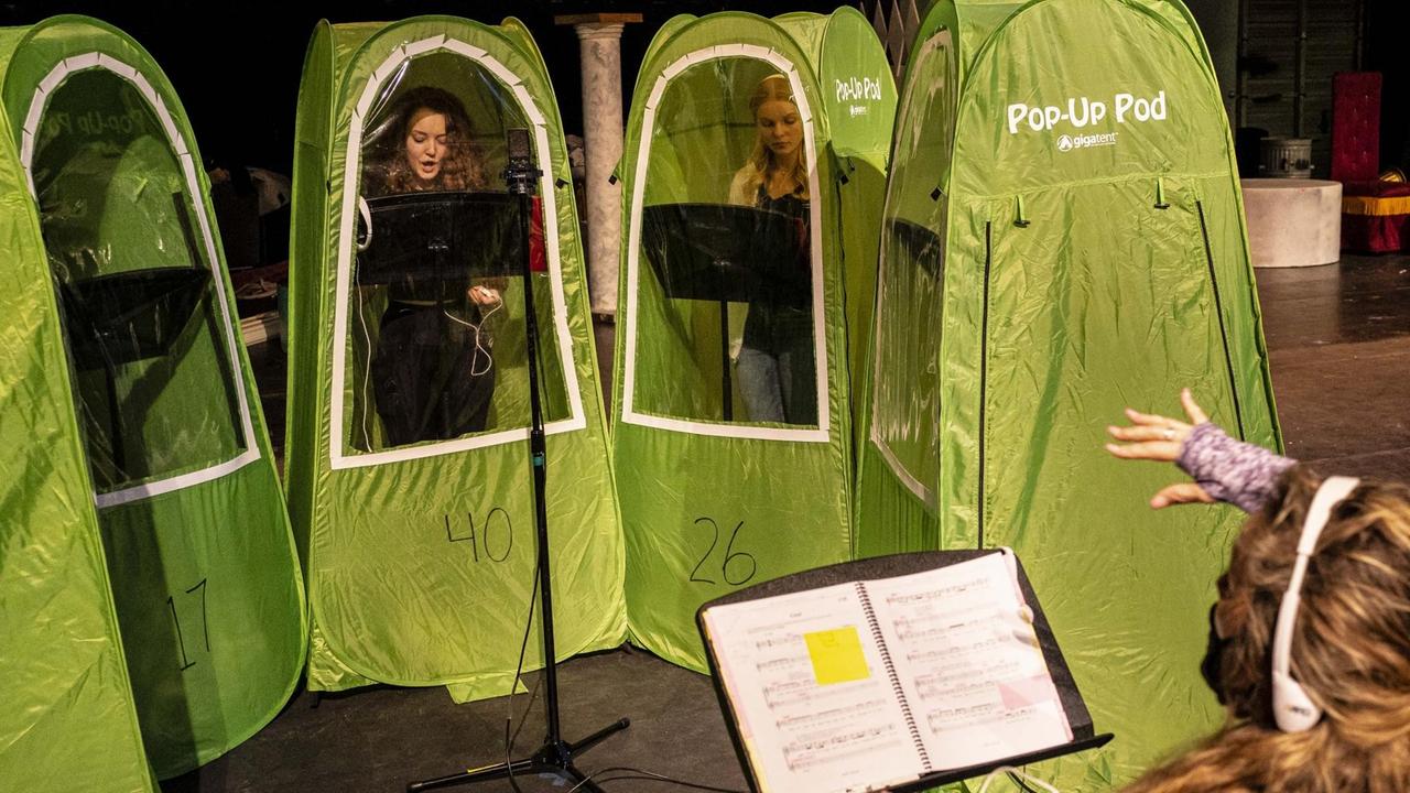 Junge Sängerinnen stehen in hellgrünen, hohen schmalen Zelten mit Sichtfenster und singen. Junge Sängerinnen stehen in hellgrünen, hohen schmalen Zelten mit Sichtfenster und singen.