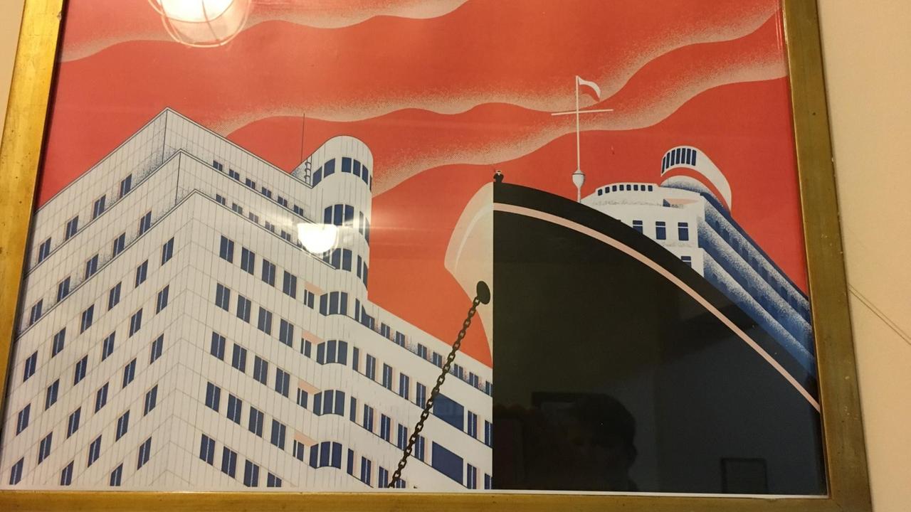 Ein Plakat zeigt ein Großes Schiff vor einer modernen Häuserfassade. Ein Plakat zeigt ein Großes Schiff vor einer modernen Häuserfassade.