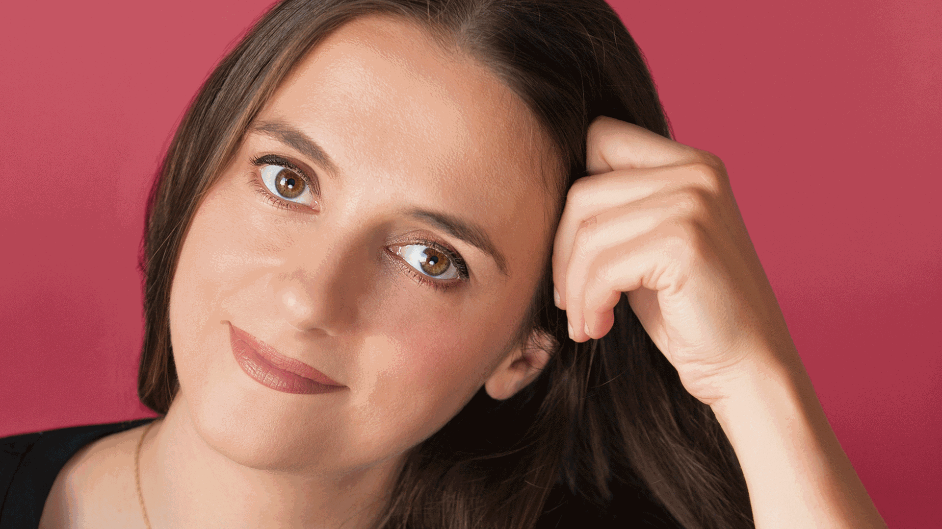 Eine braunhaarige junge Frau blickt in einem Portraitbild mit rotem Hintergrund in die Kamera. Eine braunhaarige junge Frau blickt in einem Portraitbild mit rotem Hintergrund in die Kamera.