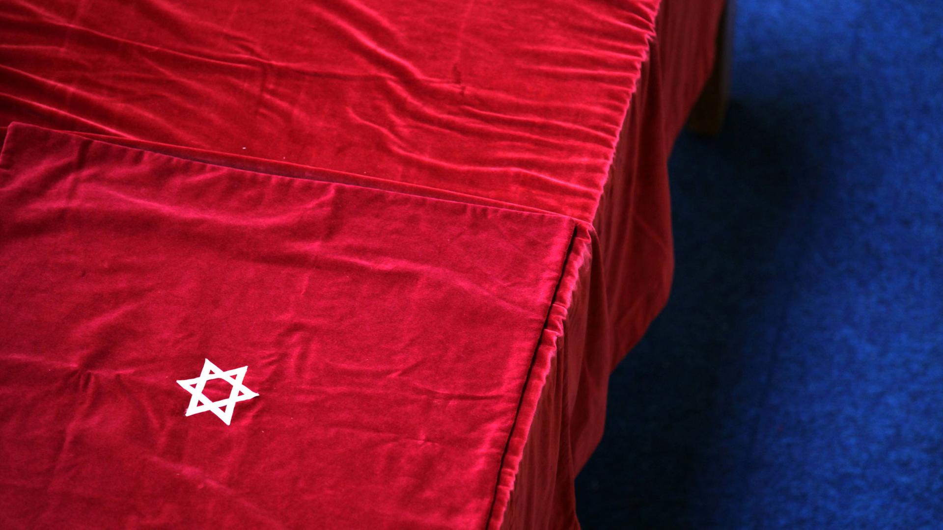Der mit rotem Samt bedeckte Tisch, auf dem die Torarollen ausgebreitet werden, in der jüdischen Gemeinde in Deventer, Niederlande. Auf dem roten Samt leuchtet ein weißer Davidstern.