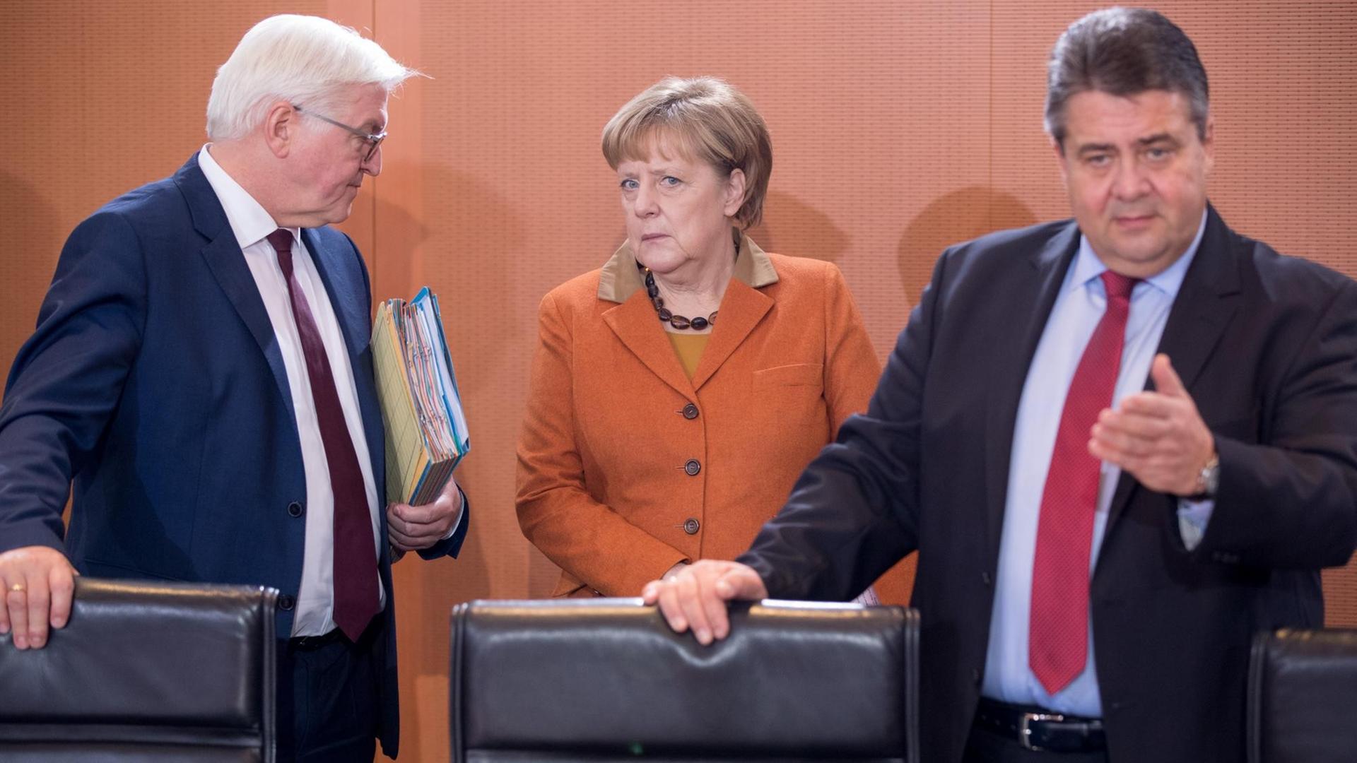 Bundesaußenminister Frank-Walter Steinmeier (SPD), Bundeskanzlerin Angela Merkel (CDU) und Bundeswirtschaftsminister Sigmar Gabriel (SPD) (v.l.) stehen am Kabinettstisch. Bundesaußenminister Frank-Walter Steinmeier (SPD), Bundeskanzlerin Angela Merkel (CDU) und Bundeswirtschaftsminister Sigmar Gabriel (SPD) (v.l.) stehen am Kabinettstisch.
