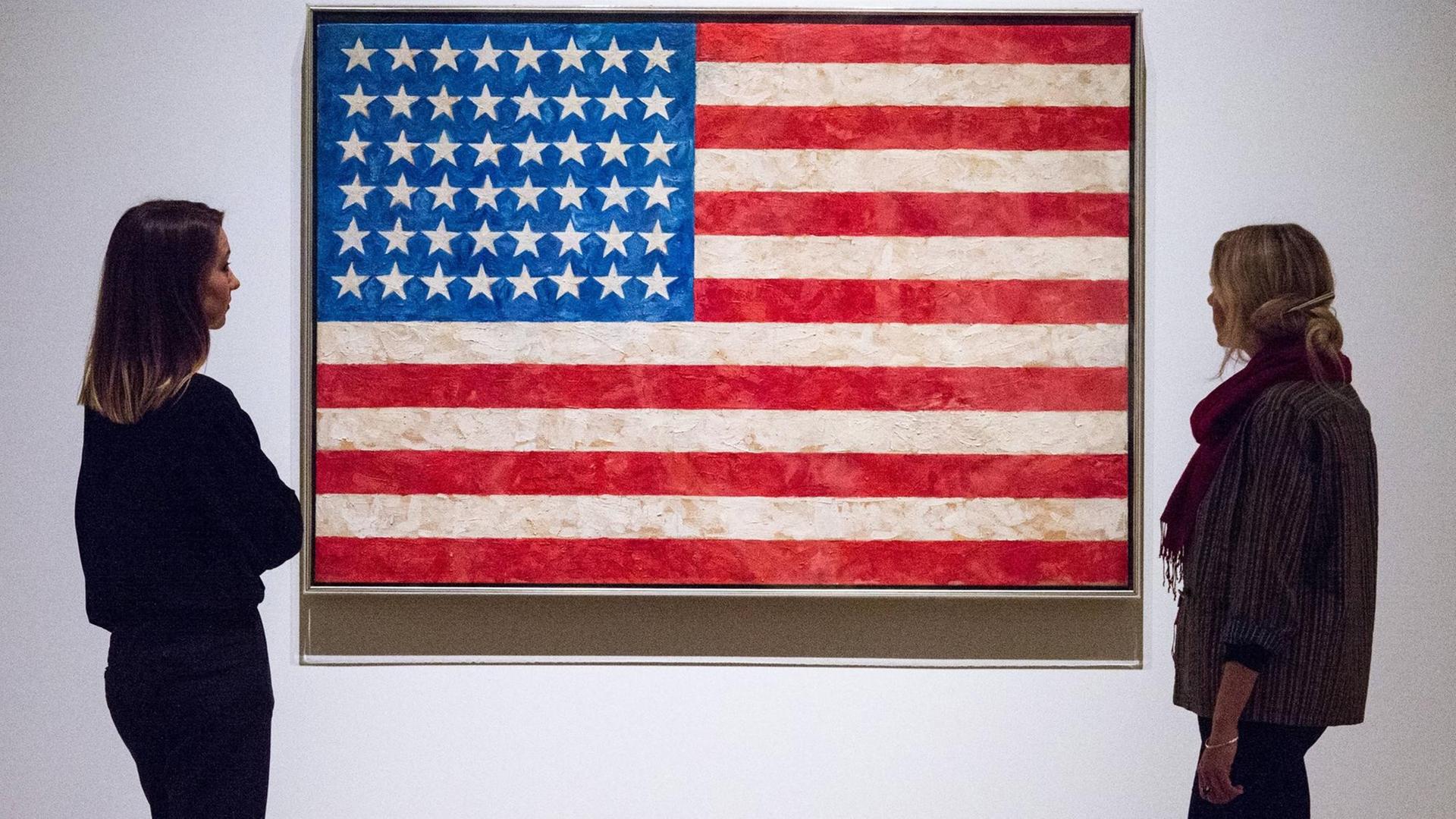 Zwei Besucherinnen betrachten Jasper Johns Gemälde "Flag" (1958) in der Ausstellung "Something Resembling Truth" in der Royal Academy, London, September 2017.