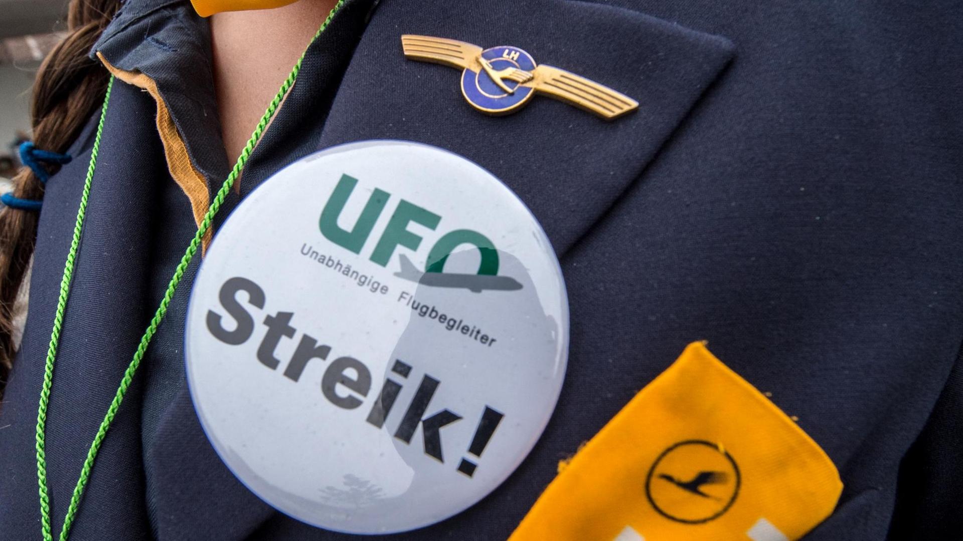 Ein Button mit der Aufschrift "UFO. Streik" ist auf der Uniform eine Flugbegleiterin zu sehen. Ein Button mit der Aufschrift "UFO. Streik" ist auf der Uniform eine Flugbegleiterin zu sehen.