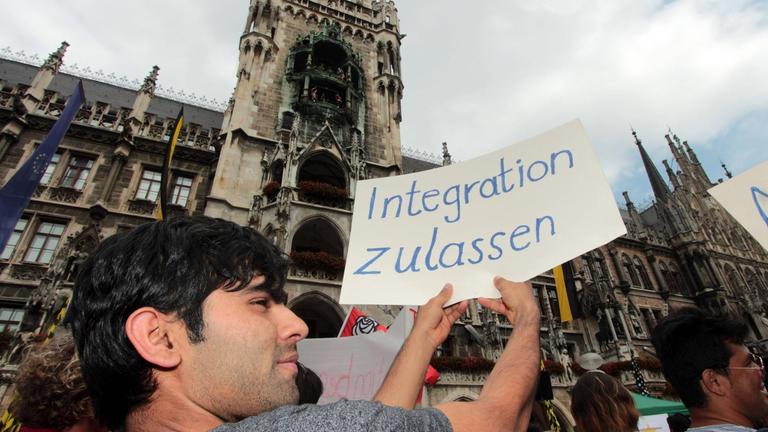 Demonstrant mit Plakat und Aufschrift "Integration zulassen"

