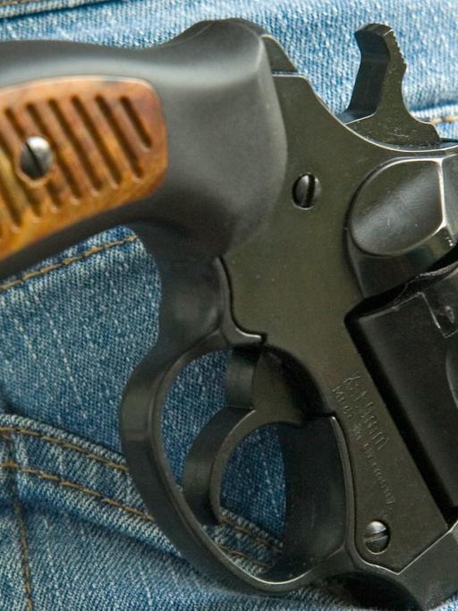 Ein Revolver Kaliber 9 mm ragt aus der Gesäßtasche einer Jeans-Hose