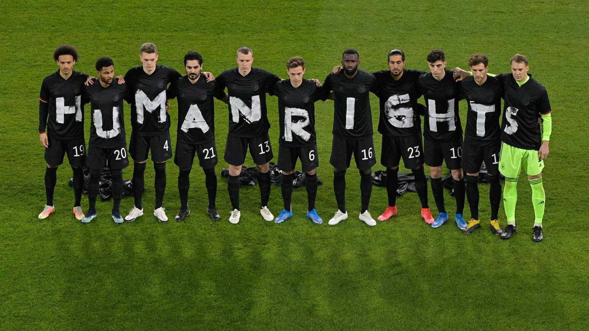 Die deutsche Fußball-Nationalelf mit Buchstaben auf Trikots, die zusammen "Human Rights", also "Menschen-Rechte", ergeben