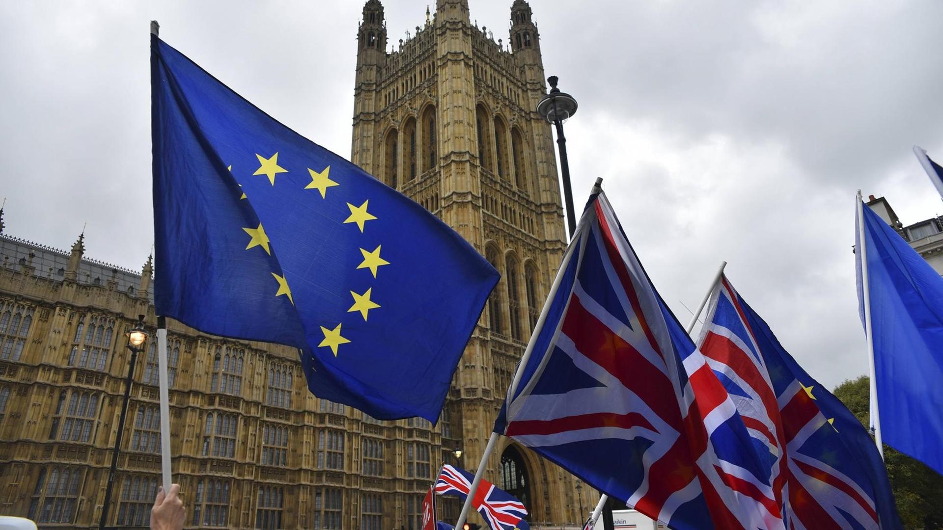 Europäische und britische Flaggen wehen vor dem britischen Parlament. 