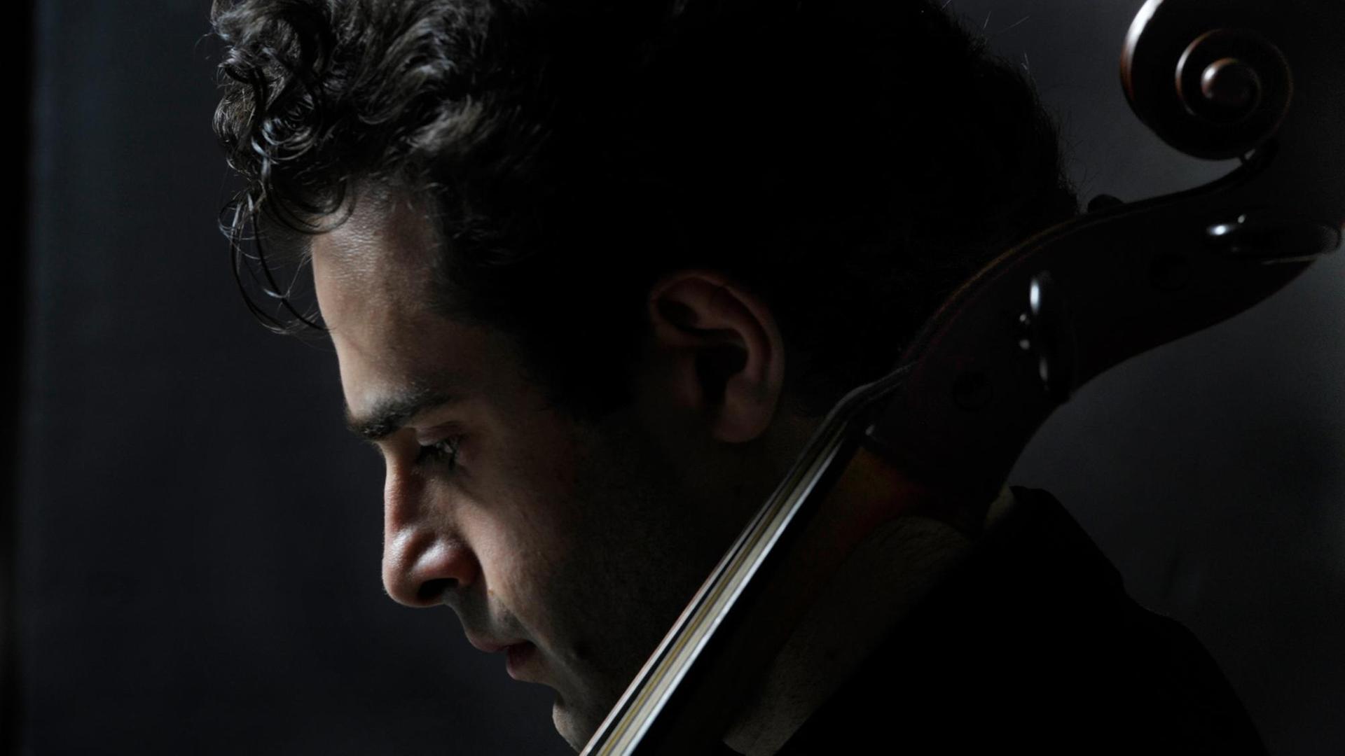 Der Kopf des Cellisten Davit Melkonyan ist von der Seite zu sehen, hinter dem Steg seines Cello. Der Kopf des Cellisten Davit Melkonyan ist von der Seite zu sehen, hinter dem Steg seines Cello.