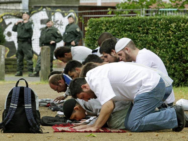 Anhänger der Salafisten beten am Samstag (09.06.2012) in Köln unter der Beobachtung der Polizei.