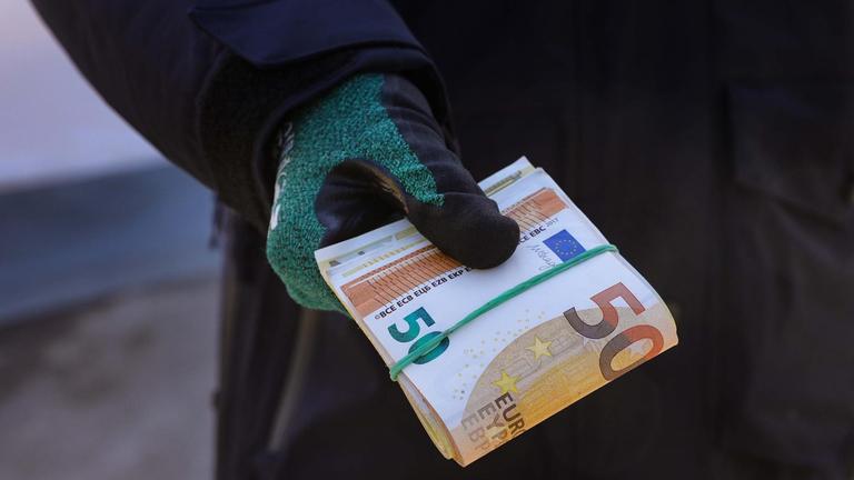 Ein Zollbeamter hält ein Bündel Geldscheine in der Hand.